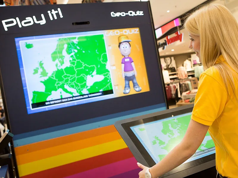 Besucherin spielt das interaktive ECE Play it! Geo-Quiz mit dem virtuellen Moderator Felix